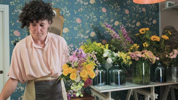 Woman arranging flowers in bouquet in floral shop