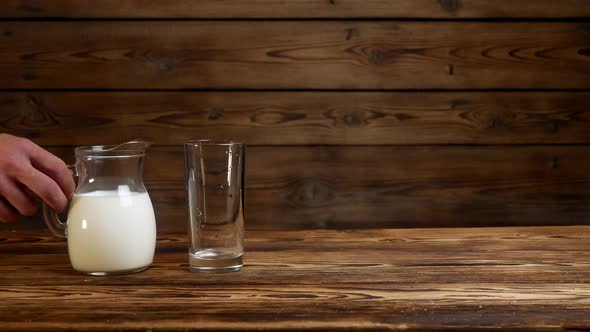 Pouring Fresh Milk Into a Transparent Glass on a Rustic Background