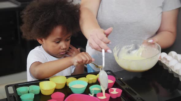 Little Black Girl with Her White Mother Lays Down the Dough in the Small Cake Moulds