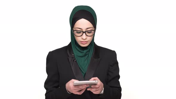 Portrait of Smart Arabic Woman in Headscarf Typing Text Messages or Browsing on Digital Tablet