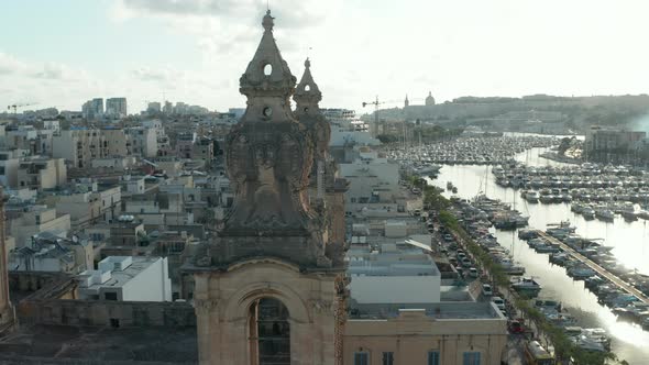 Close Up of Two Church Bell Towers on Malta with Sailboats and Yacht Port in Background on Beautiful