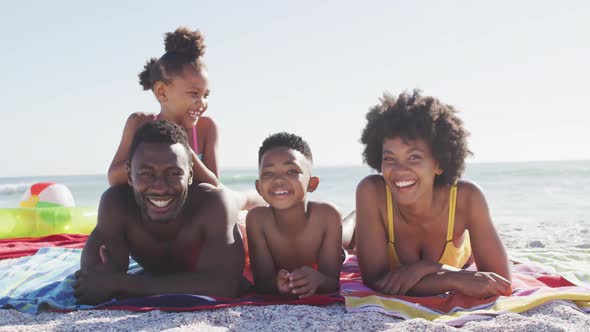 Portrait of smiling african american family lying on sunny beach