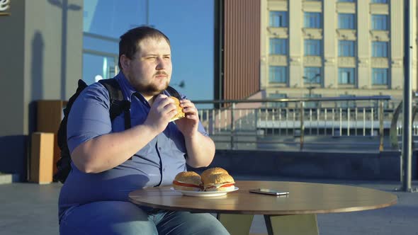 Male Office Worker Eating Burger for Lunch Outdoors, Junk Food Nutrition Obesity