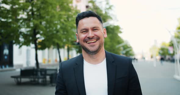 Portrait of Joyful Middle-aged Man Laughing Looking at Camera Outdoors in City