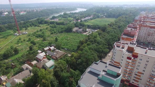 Aerial shot approaching a complex of high rise public housing apartments in front of a nature park