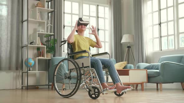 Asian Kid Girl Sitting In A Wheelchair While Wearing Virtual Reality Goggles At Home