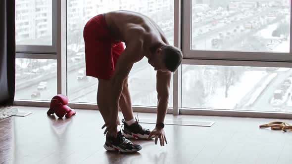 Muscular Shirtless Man Leaning Down and Touching the Floor with His Palms