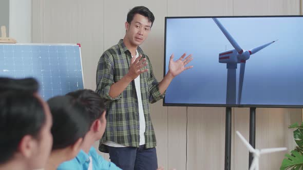 Asian Man Engineer With Solar Cell Presenting About The Wind Turbine At The Office