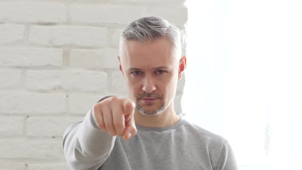 Middle Aged Man Pointing at Camera Sitting in Office