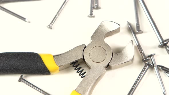 Wire Cutters with Yellow, Gray Handle on White Among Nails, Rotation, Close Up