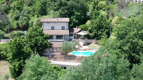 Slow motion aerial overview of small villa in woodland