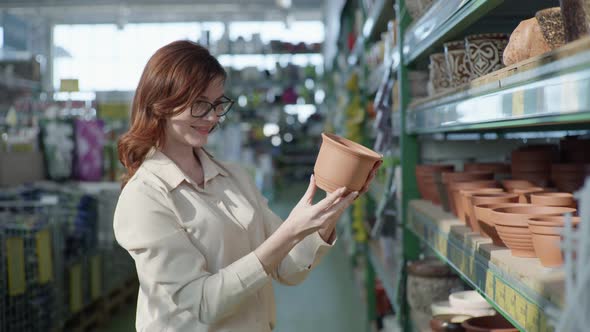 House and Garden, Young Smiling Female Customer in Glasses for Vision Stands with Clay Pot for Home