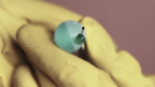 Syringe Needle with Liquid Dripping Drops of Medication in Doctor Hands