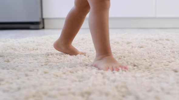 Bare Legs of Unrecognizable Toddler Learning to Walk on Carpet