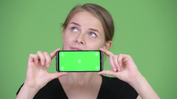 Young Beautiful Businesswoman Thinking While Showing Phone