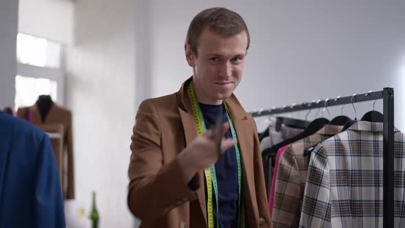 Confident Gay Male Fashion Designer Posing in Shop in Slow Motion with Scissors