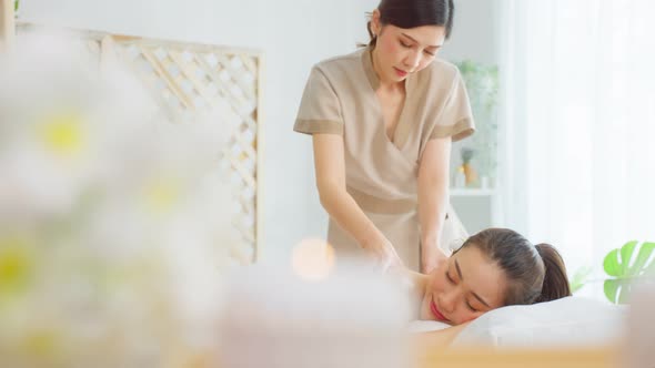 Asian young woman feeling happy and relax during back massage with oil in spa beauty salon