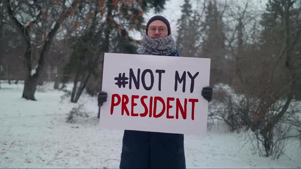 Man with a sign #Not My President posing for social media attention in a park