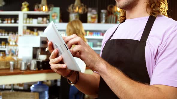 Waiter using digital tablet at counter