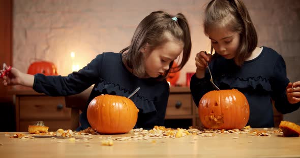 Two Cute Little Girls Are Cutting a Pumpkin on the Table for Halloween