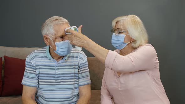 Senior Couple Measures Temperature with Contactless Digital Thermometer During Coronavirus Lockdown