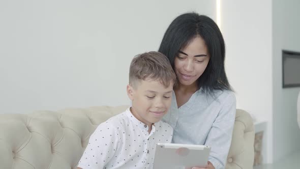 Portrait of Happy African American Woman and Boy Watching Funny Video on Tablet. Positive Young