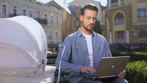 Man Working Laptop and Smiling to Infant in Carriage, Multitasking, Freelance