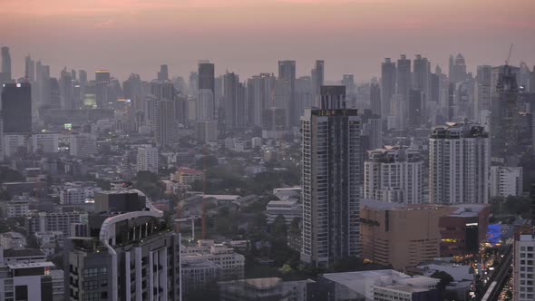 Panning view of business area in Bangkok, Thailand, showing buildings and traffic in twilight time