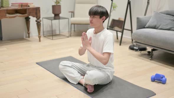 Young Asian Man Meditating on Yoga Mat at Home