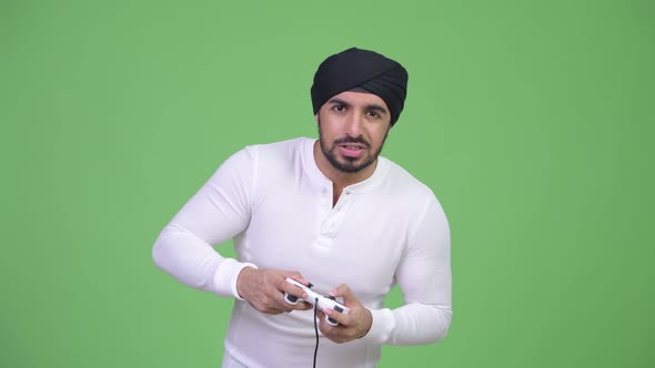 Young Stressed Bearded Indian Man Playing Games and Losing
