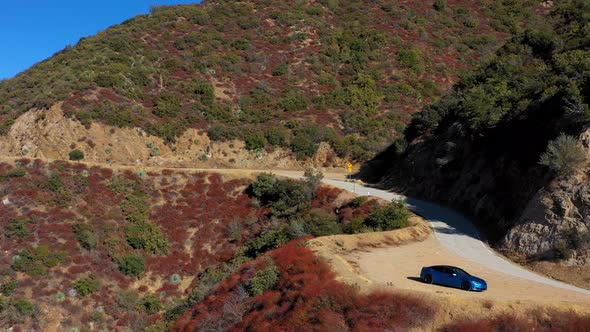 Panning left aerial shot of a blue Tesla Model S on Mt. Baldy in Southern California.