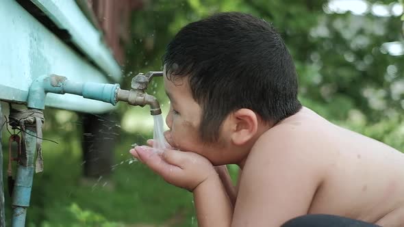 Slow motion of Asian boy drinking outdoors fresh water from tap, Saving water concept.