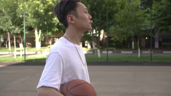 Young Asian Sporty Man with a Basketball Outdoors