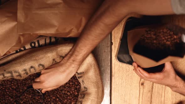 Closeup View From Above in Slow Motion of Male Hand Grabbing Roasted Robusta or Arabica Coffee Beans