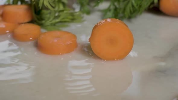 Piece Of Cut Carrot Rolling On Wet Surface In The Kitchen. close up, slow motion