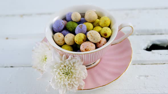 Cup filled with painted chocolate Easter eggs and white flower