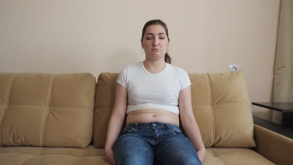 Young Woman Sits on the Sofa and is Sad