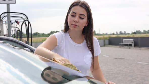 Attractive Happy Joyful Female Driver Wipe Windshield on Her Car Using Rag in Selfservice Car Wash