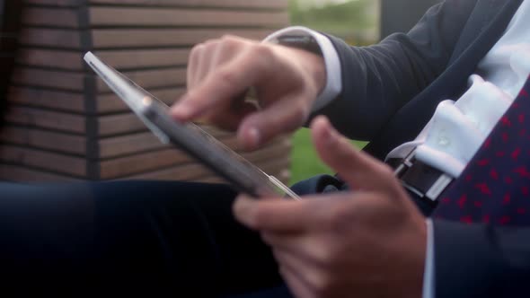 Close Up Successful Businessman in Suit Sits Outside in Park and Use Tablet Writes with Finger