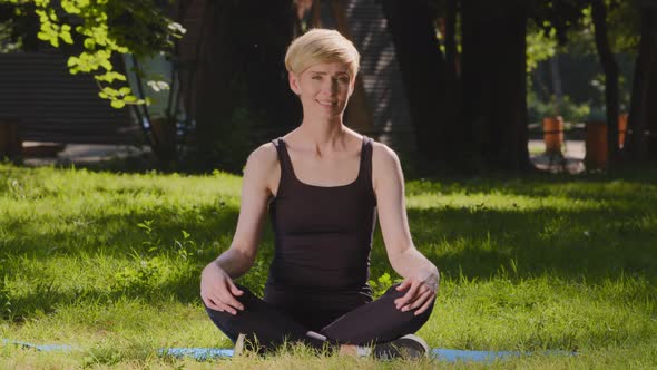 Middleaged Caucasian Sporty Slim Woman Female Trainer with Short Haircut Sitting in Lotus Position