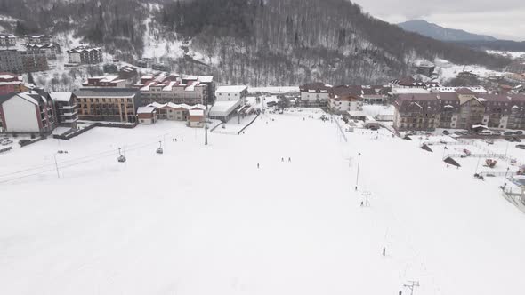 Aerial view of the ski resort with snowy mountain slopes and winter trees. 