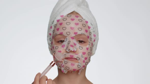 Lovely Young Smiling Child Girl Applying Cosmetic Moisturizing Face Mask Use Massage Roller