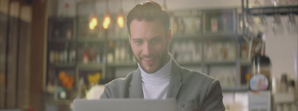 Smiling man working on laptop in cafe