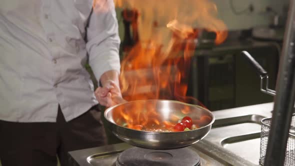 Cook Is Flambeing Vegetables in a Saute Pan, Tossing It Up , Close-up