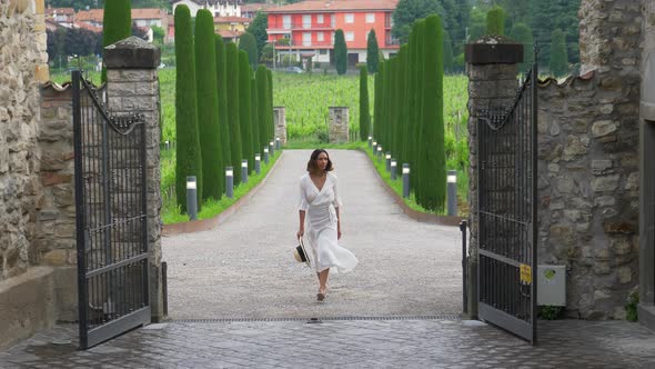 A woman walking on a path with cypress trees while traveling at a luxury resort in Italy, Europe