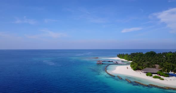 Daytime overhead tourism shot of a white sandy paradise beach and aqua blue ocean background in 4K