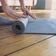 Yoga Practitioner Rolls Mat on Wooden Floor After Training - VideoHive Item for Sale