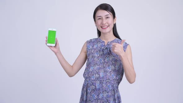 Happy Pregnant Asian Woman Showing Phone and Giving Thumbs Up