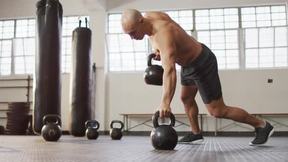 Fit caucasian man working out with kettle bells at the gym