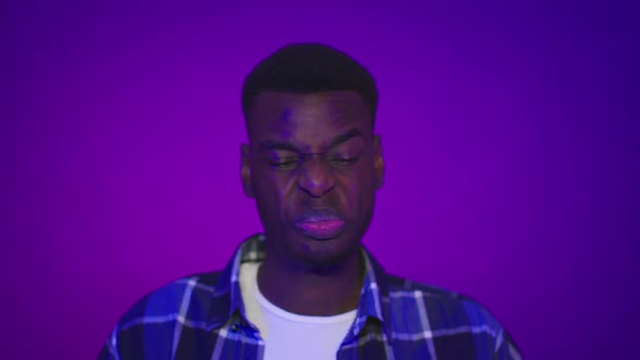 Disgusted African Man Frowning Feeling Bad Smell Over Purple Background